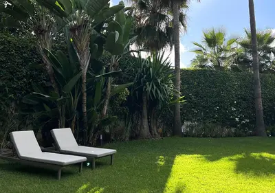 two white chairs sitting on the grass in a yard at Villa de luxe avec piscine privée au cœur de Casablanca, Maroc in Casablanca