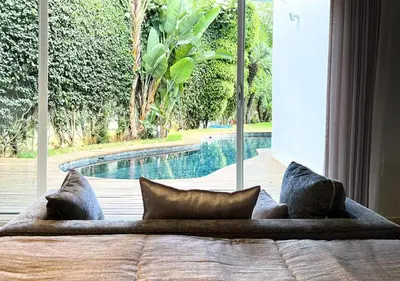 a bed with pillows in a room with a swimming pool at Villa de luxe avec piscine privée au cœur de Casablanca, Maroc in Casablanca