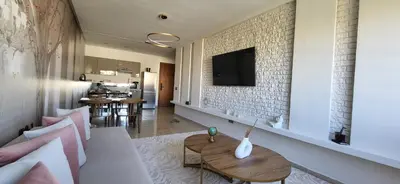 a living room with a table and a tv on a wall at Le Cocon d'Oasis - Location journalière Casablanca in Casablanca