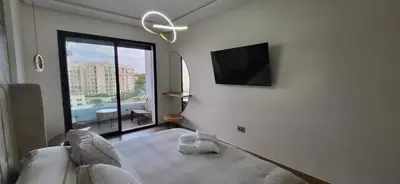 a white bedroom with a flat screen tv on a wall at Le Cocon d'Oasis - Location journalière Casablanca in Casablanca