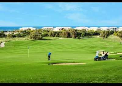a man playing golf on a green with a golf cart at Superbe Appartement Bord de mer in Bouznika