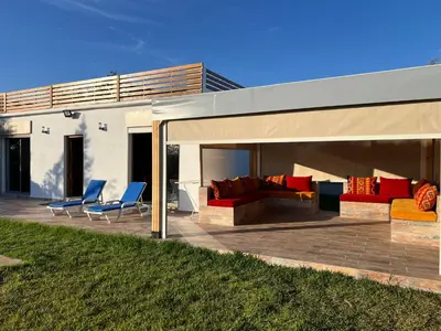 a patio with couches and chairs under a roof at Maison de Campagne in Dar SaÃ¯d Ben Hajj
