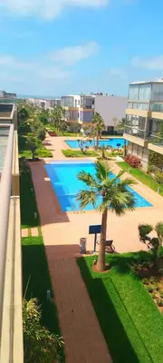 a view of a swimming pool with a palm tree at Sidi Rahal Bleu Beach family in Sidi Rahal