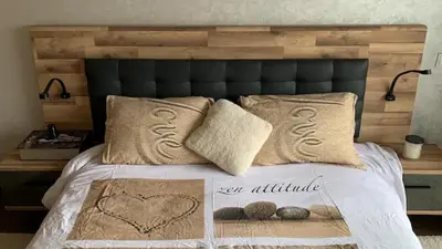 a bed with a wooden headboard and pillows on it at Nouaceur Garden in Casablanca