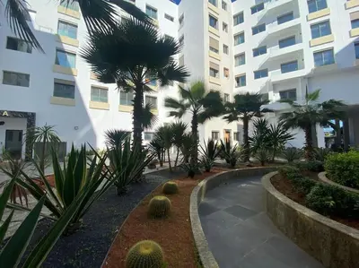 a courtyard with palm trees in front of a building at Corniche Casablanca - Black New in Casablanca