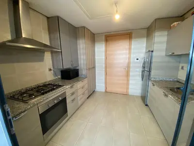 a kitchen with a stove top oven next to a refrigerator at Prestigia Appartement Luxueux in Rabat