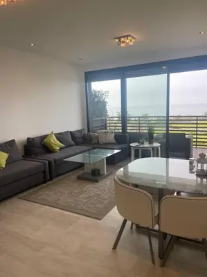 a living room with a couch and a glass table at Nice appartement pool & sea view in Dar Bouazza