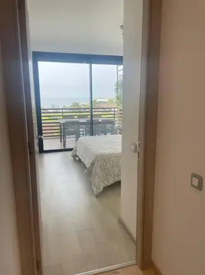 a bedroom with a bed and a view of a balcony at Nice appartement pool & sea view in Dar Bouazza