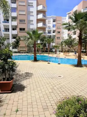 a courtyard with palm trees in front of a building at La perle in Nouaceur