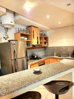 a kitchen with a granite counter top and a refrigerator at La perle in Nouaceur