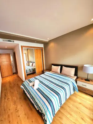 a bedroom with a large bed with a striped blanket at La perle in Nouaceur