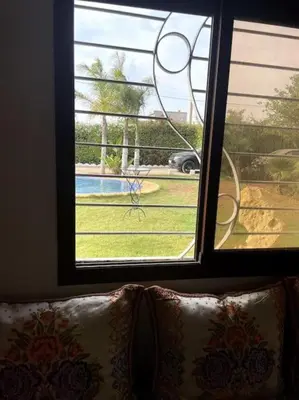 a window with a view of a yard and a pool at Villa avec piscine et jardin privés in Casablanca