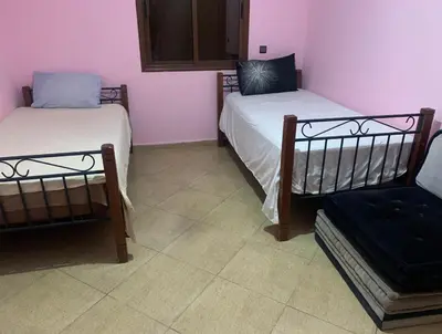 a room with two beds and a chair in it at Villa avec piscine et jardin privés in Casablanca