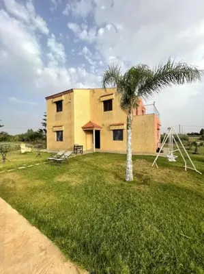 a building with a palm tree and a playground at Villa avec piscine et jardin privés in Casablanca