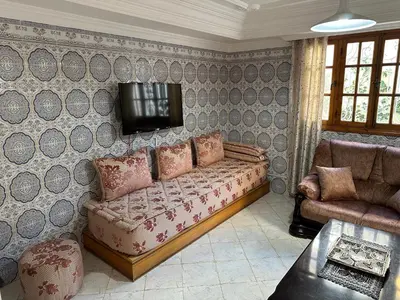 a living room with a couch and a tv on a wall at Rez-de-jardin à Mohammedia in Mohammedia
