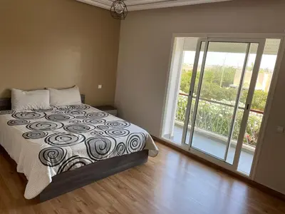 a bedroom with a bed and a large window at OASIS BEACH APPARTEMENT MEUBLé RESIDENCE FERMÉE AVEC PISCINE TAMARIS 2 SIDI RAHAL in Sidi Rahal