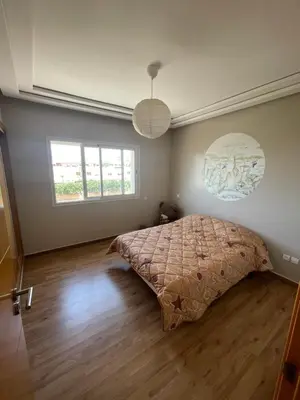 a bedroom with a large bed and a wooden floor at OASIS BEACH APPARTEMENT MEUBLé RESIDENCE FERMÉE AVEC PISCINE TAMARIS 2 SIDI RAHAL in Sidi Rahal