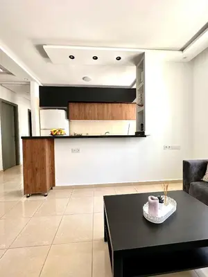 a living room with a black table and a kitchen at chez mehdi in Skhirat