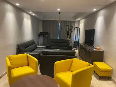 a living room with two yellow chairs and a tv at APPARTEMENT HAUT STANDING proche gare casa voyageur in Casablanca