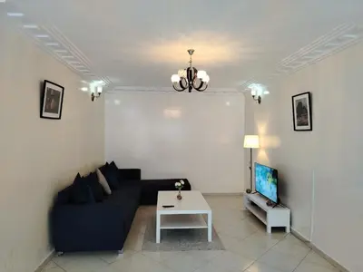 a living room with a couch and a tv at Appartement Casa Voyageurs in Casablanca