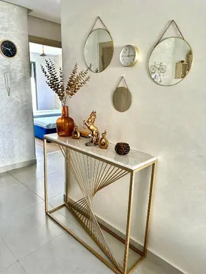 a gold console table in a room with mirrors at Appartement Cozy avec piscine in Sidi Rahal