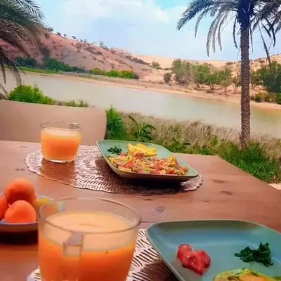 a table with a plate of food and a bowl of juice at Lake House Boulaouane in El Jadida