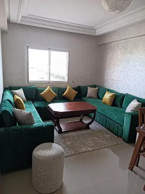 a living room with a green couch and a table at Appartement avec piscine à Mohammedia Plage à 5min in Mohammedia