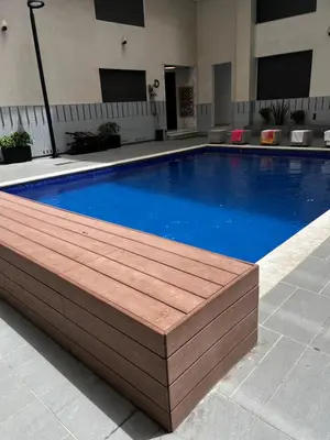 a large swimming pool with a wooden deck around it at Magnifique duplex moderne à 1 minute à pied de la plage- Résidence Miramar Mohammedia in Mohammedia