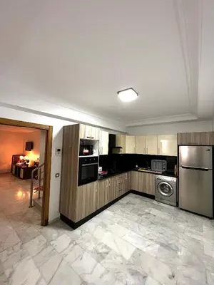 a kitchen with stainless steel appliances and a living room at Magnifique duplex moderne à 1 minute à pied de la plage- Résidence Miramar Mohammedia in Mohammedia
