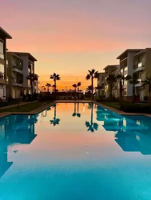a swimming pool in front of some apartment buildings at Cosy Apartment with sea view in Sidi Rahal