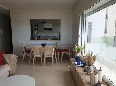 a living room with a table and chairs and a kitchen at Appartement Front de mer avec vue Panoramique in Casablanca