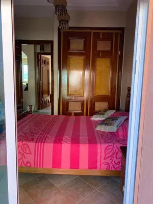 a bedroom with a large bed with a pink blanket at Appartement mohamedia Ricoflores vue sur piscine in Mohammedia