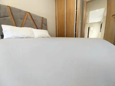 a large white bed with white pillows in a room at Cosy appartement proche de l'aéroport mohamed 5 in Deroua
