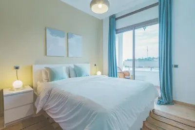 a white bedroom with a large bed and a large window at lovely 2 bedroom vacation home with pool/beach in Skhirat