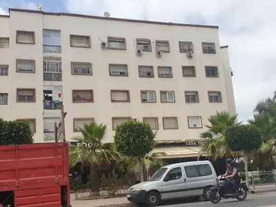 a person riding a motorcycle in front of a building at Appartement Meublé AIN SEBAA in Aïn Sebaa