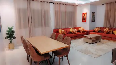 a living room with a table and a red couch at Appartement Nova - Costa Bouznika in Bouznika