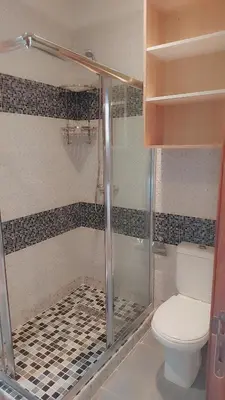 a bathroom with a toilet and a glass shower at Appartement Nova - Costa Bouznika in Bouznika
