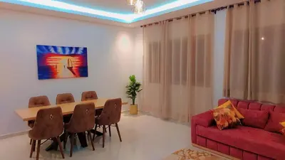 a living room with a red couch and a table and chairs at Appartement Nova - Costa Bouznika in Bouznika