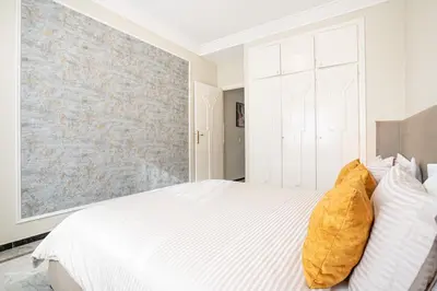 a bedroom with a white bed and a brick wall at Grand Appartement Vue mer à Ain Diab - Calme Absolu in Casablanca