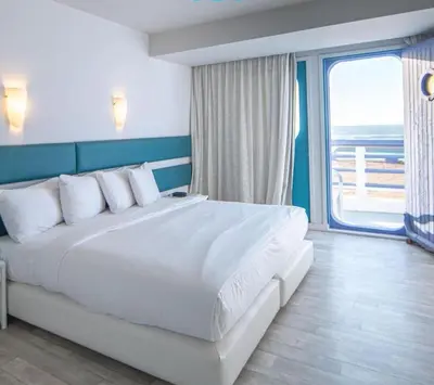 a bedroom with a large white bed with a large window at Hotel Tropicana in Casablanca