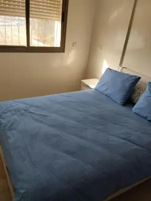 a bedroom with a blue bed with a window at Appartement Cozy Louizia in Ben Yakhlef