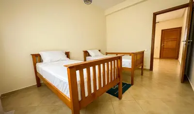 two twin beds in a room with a hallway at Ferme d'hôte Evasio in Sidi Rahal