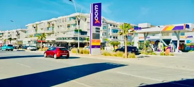 a red car driving down a street in front of a building at Residence Al Kawtar in Mohammedia