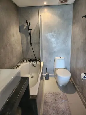 a bathroom with a toilet and a tub and a sink at Appartement Luxueux vue Mer dans Résidence avec piscines et jardin in Dar Bouazza