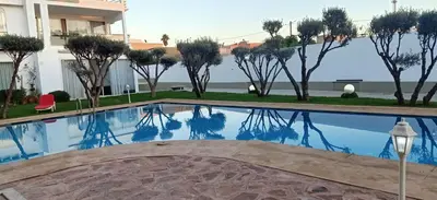 a swimming pool in the middle of a building with trees at Appartement Luxueux vue Mer dans Résidence avec piscines et jardin in Dar Bouazza