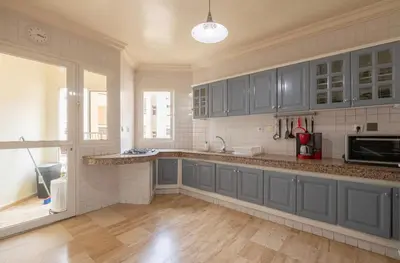 a kitchen with blue cabinets and a counter top at Cosy Apartment 200 M2 Hay Ryad Rabat in Rabat