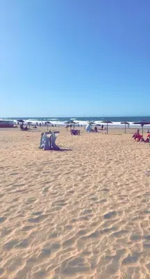 a sandy beach with chairs and umbrellas on it at Molto carino ben solare in Sidi Rahal
