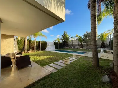 a backyard with a swimming pool and palm trees at Luxury Villa Oasis, Bouznika Bay in Bouznika