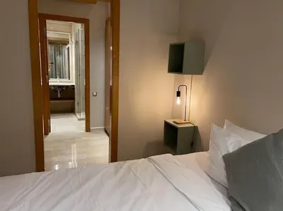 a bedroom with a white bed with a lamp and a hallway at Luxury Villa Oasis, Bouznika Bay in Bouznika