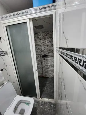 a bathroom with a toilet and a glass shower door at chez Jalil in Aïn ej Jmel